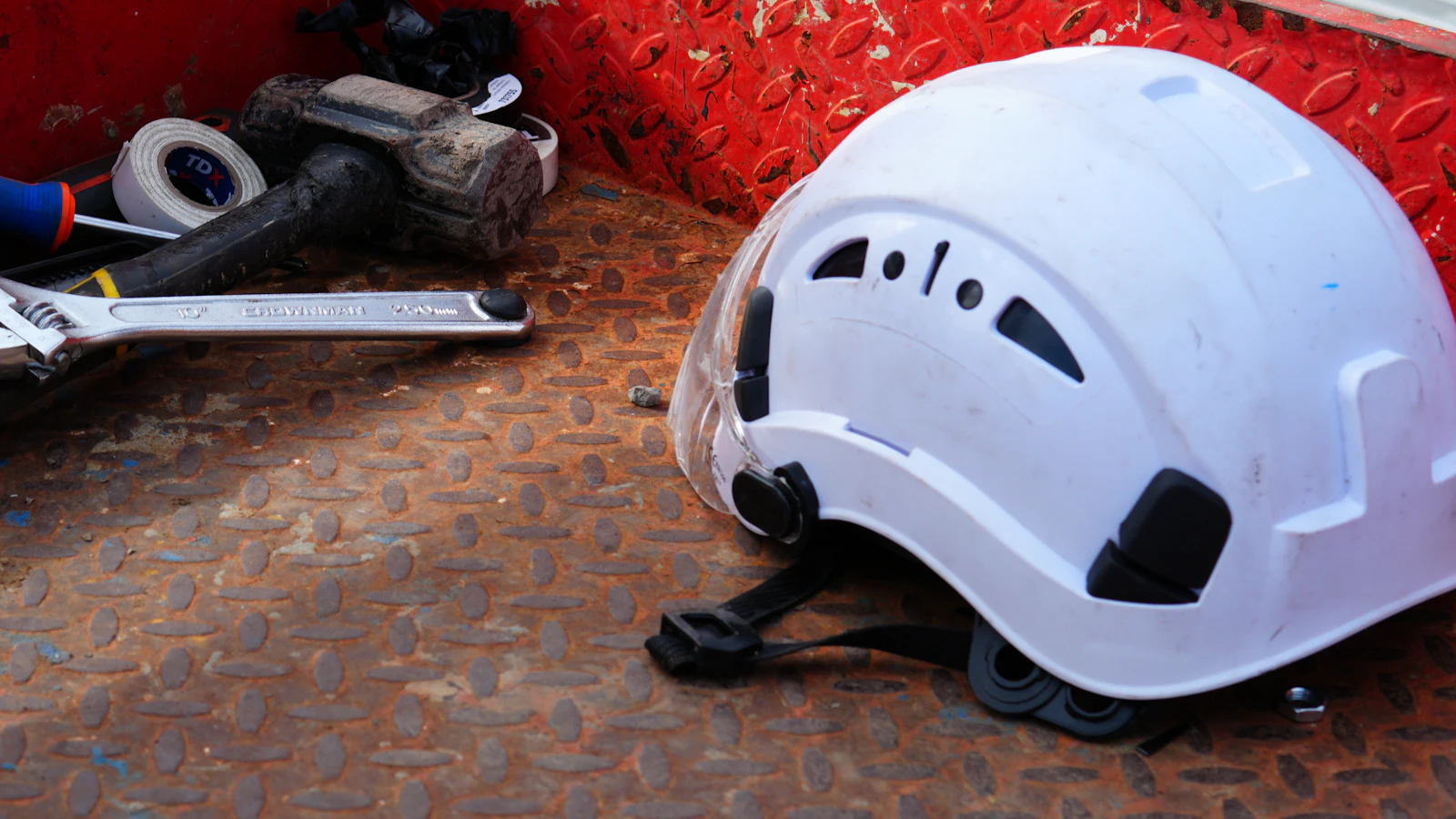 A hard hat and hand tools in the tray of a work trailer